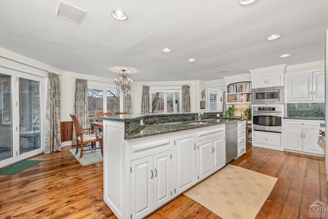 kitchen with a notable chandelier, a sink, open shelves, white cabinetry, and appliances with stainless steel finishes