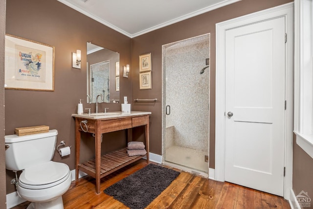 bathroom featuring ornamental molding, a sink, a shower stall, and wood finished floors