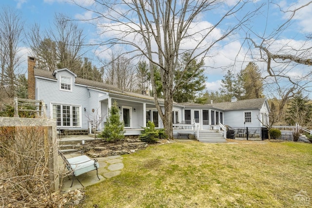 rear view of property with a chimney, a sunroom, french doors, and a yard