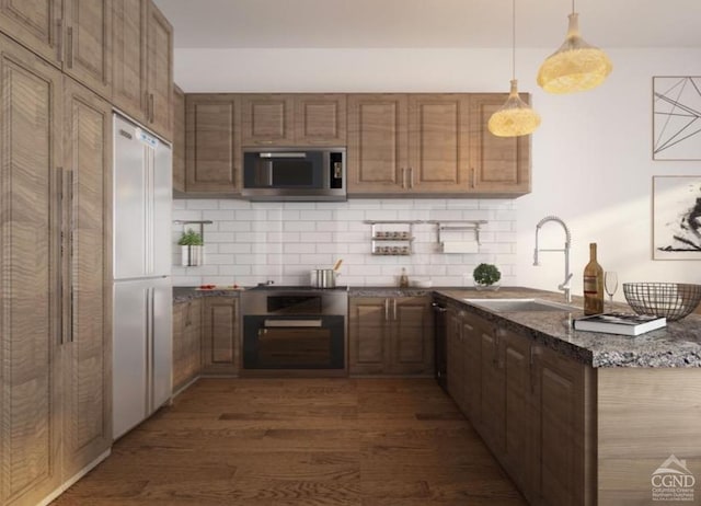 kitchen featuring sink, decorative light fixtures, dark stone countertops, dark hardwood / wood-style floors, and built in refrigerator