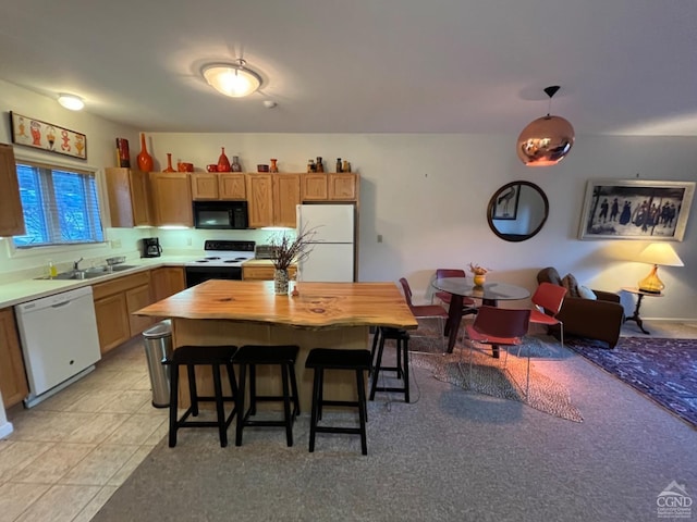 kitchen with light tile patterned floors, white appliances, a breakfast bar, a sink, and decorative light fixtures