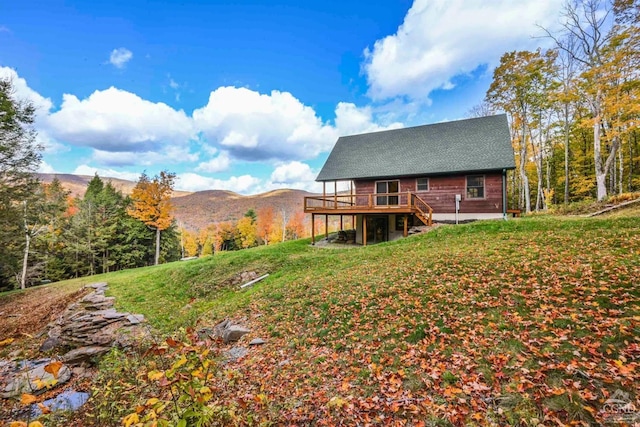 back of property with a deck with mountain view and a yard