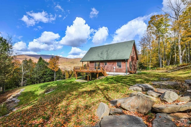 rear view of property with a lawn and a deck with mountain view