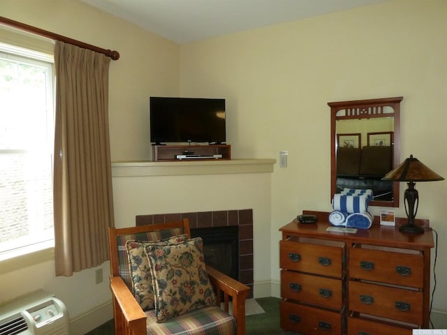 living area with a tiled fireplace and a wall mounted AC