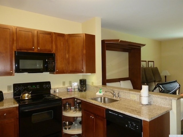 kitchen featuring light stone countertops, sink, kitchen peninsula, and black appliances