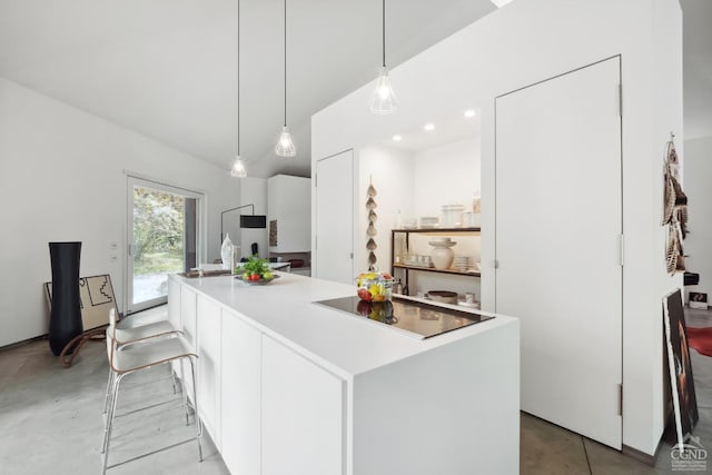 kitchen with white cabinets, a kitchen island, black electric stovetop, and hanging light fixtures