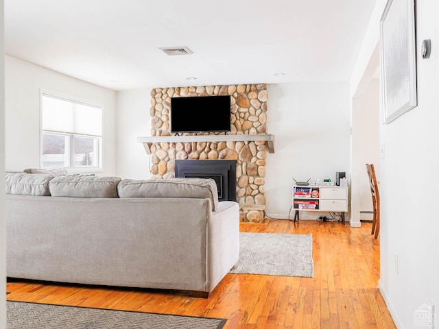 living room featuring wood-type flooring, a fireplace, and baseboard heating