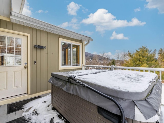 snow covered patio with a hot tub and a mountain view