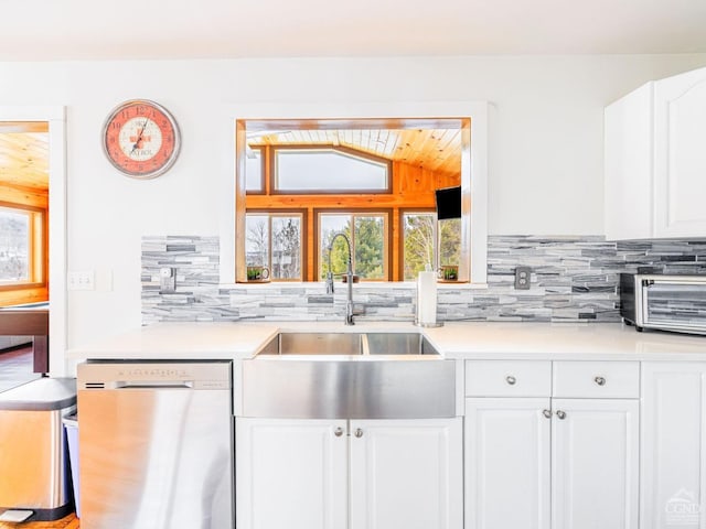 kitchen featuring lofted ceiling, sink, tasteful backsplash, dishwasher, and white cabinets