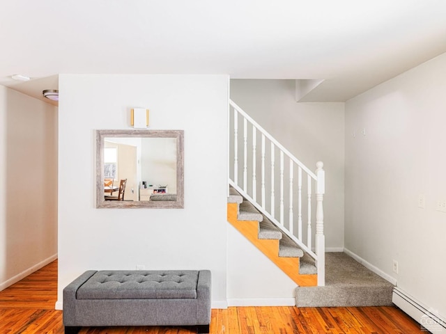 staircase with hardwood / wood-style floors and a baseboard radiator