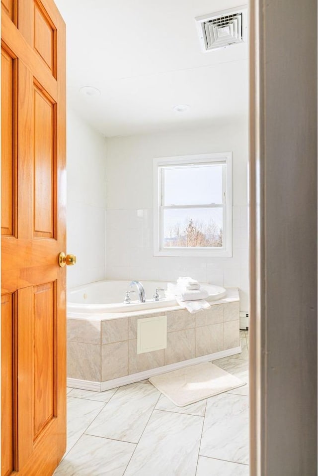 bathroom with a baseboard heating unit and tiled bath