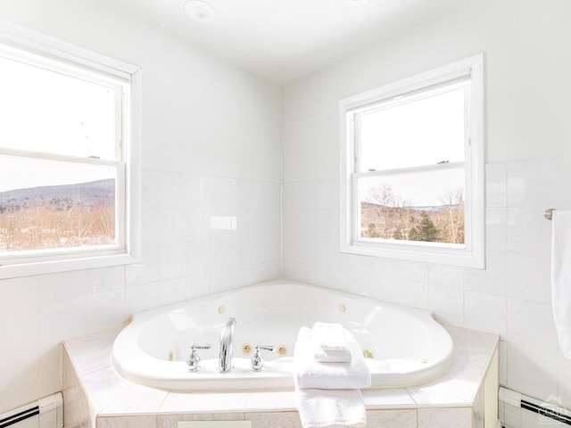 bathroom with tiled tub and a baseboard heating unit