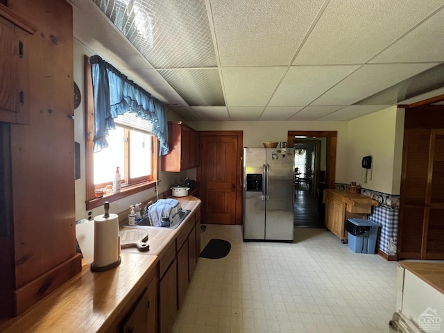 kitchen with a paneled ceiling, sink, and stainless steel refrigerator with ice dispenser