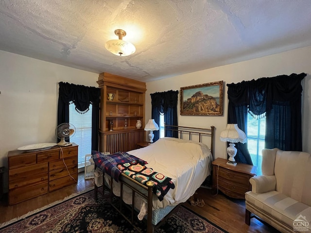 bedroom with dark hardwood / wood-style floors and a textured ceiling