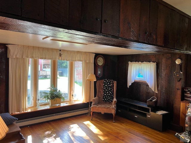 living area with light wood-type flooring, baseboard heating, and wood walls