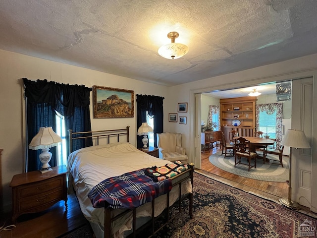 bedroom featuring multiple windows, hardwood / wood-style floors, and a textured ceiling