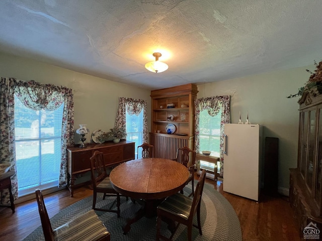 dining room featuring dark wood-type flooring and a textured ceiling