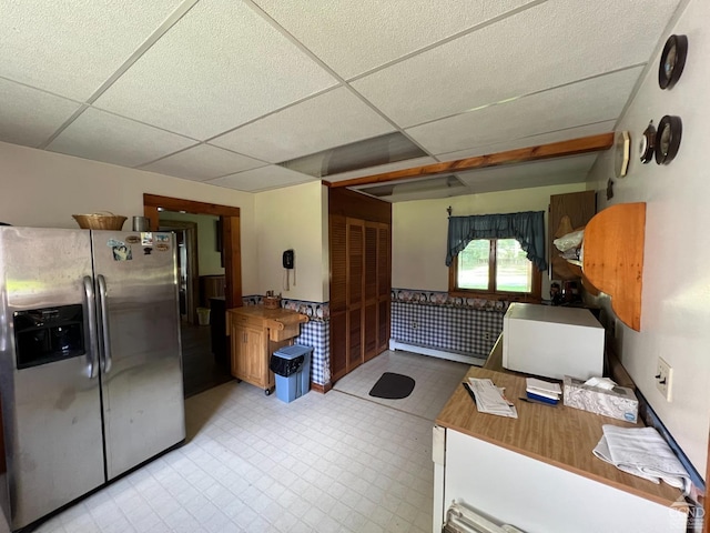 interior space featuring a paneled ceiling and stainless steel fridge with ice dispenser