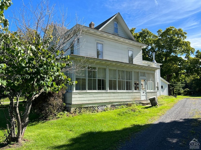 view of side of property with a yard and a sunroom