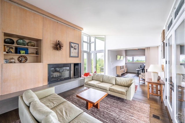 living room with built in features, lofted ceiling, and dark wood-type flooring