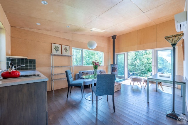 dining room with an AC wall unit, a wood stove, wooden walls, and dark hardwood / wood-style flooring