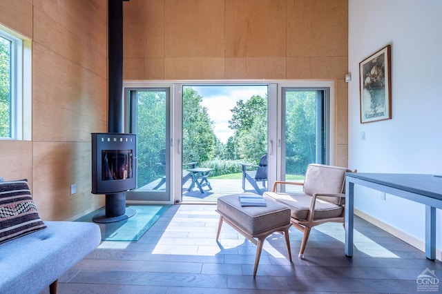 interior space with a wood stove, a wealth of natural light, and a towering ceiling