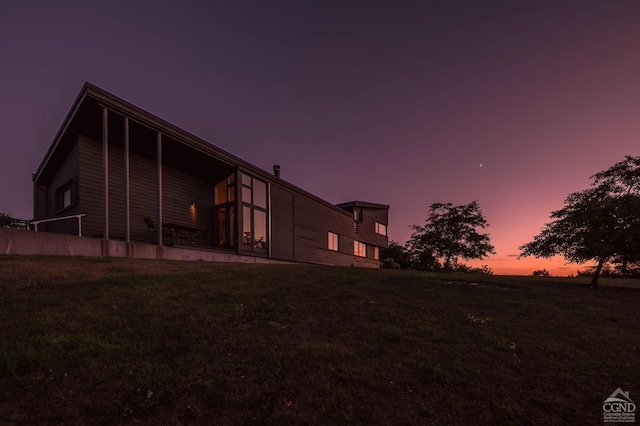 back house at dusk featuring a yard