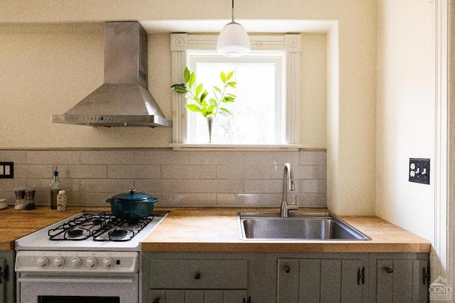 kitchen featuring a sink, decorative backsplash, gas range gas stove, and wall chimney range hood