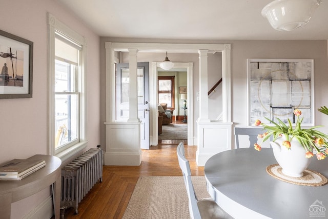 dining area featuring a wealth of natural light, radiator, parquet floors, and ornate columns