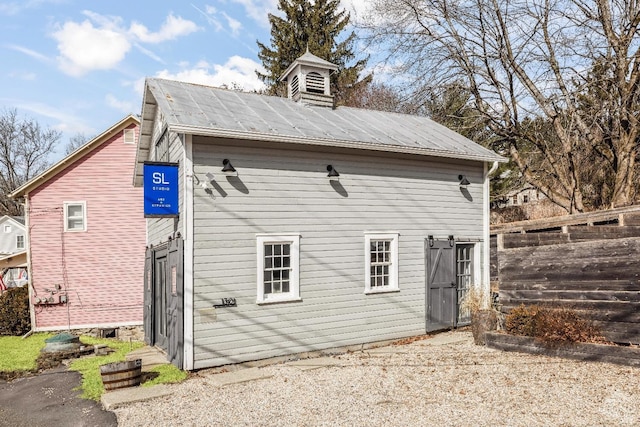 back of property featuring fence and metal roof