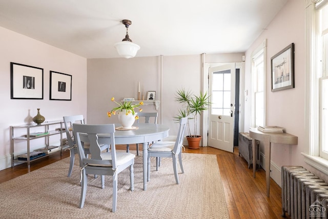 dining space with baseboards, radiator, and hardwood / wood-style flooring