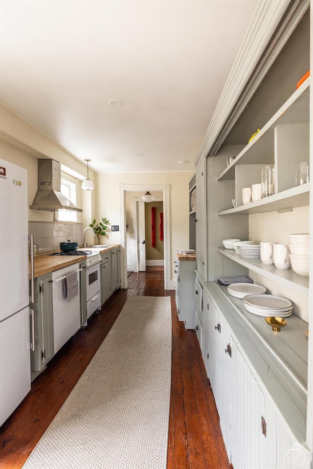 kitchen featuring tasteful backsplash, wall chimney range hood, dark wood-style floors, white appliances, and a sink