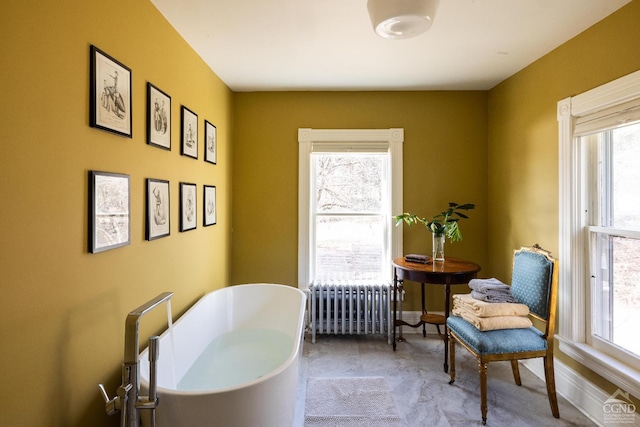 bathroom with a soaking tub, radiator, and baseboards