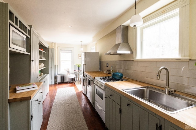 kitchen featuring radiator, wooden counters, a sink, wall chimney exhaust hood, and white gas range