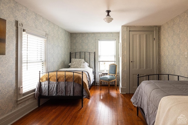 bedroom featuring baseboards, radiator, hardwood / wood-style floors, and wallpapered walls