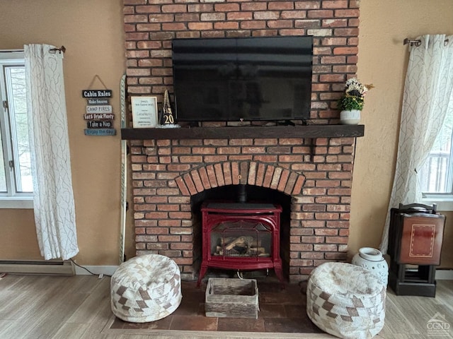 details with a wood stove, a baseboard heating unit, baseboards, and wood finished floors