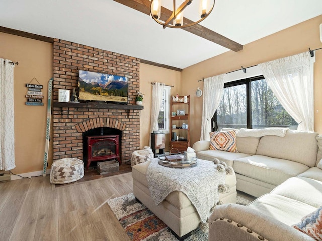 living room with a notable chandelier, wood finished floors, baseboards, a brick fireplace, and beam ceiling