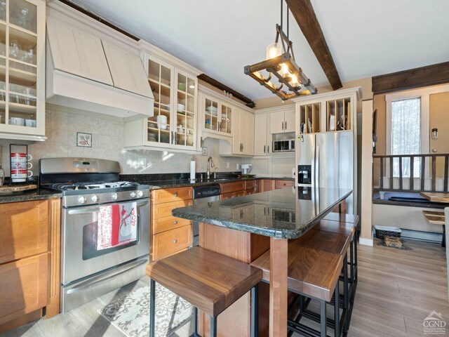 living room with a fireplace, a chandelier, baseboards, wood finished floors, and beamed ceiling