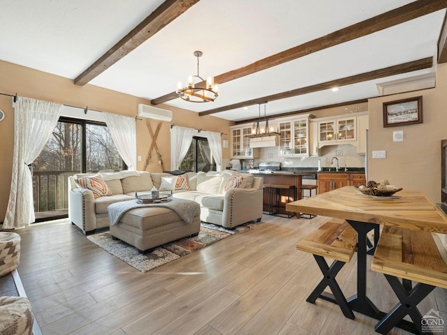 living area featuring light wood-style flooring, beam ceiling, a chandelier, and an AC wall unit