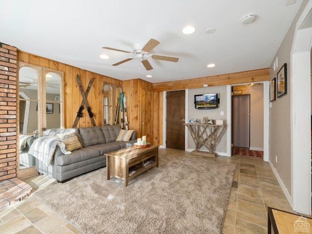 living area featuring ceiling fan, stone finish flooring, recessed lighting, and wooden walls