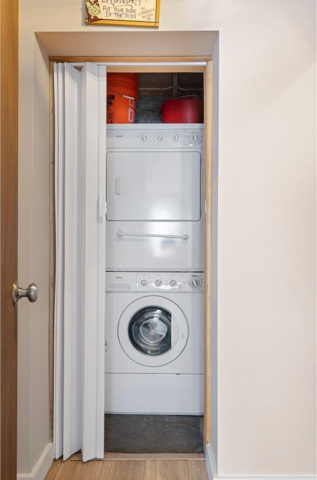 laundry area with light wood finished floors, laundry area, and stacked washer and clothes dryer