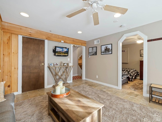 living area featuring arched walkways, recessed lighting, visible vents, a ceiling fan, and stairway