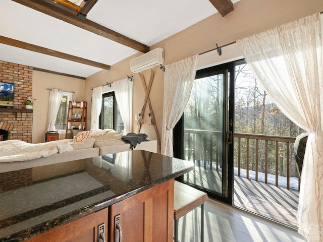 kitchen featuring dark stone counters, an AC wall unit, open floor plan, and beam ceiling