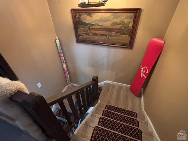 stairway with wood finished floors and baseboards