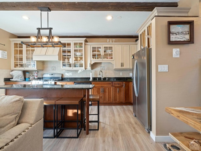 kitchen with a breakfast bar, stove, hanging light fixtures, stainless steel fridge, and glass insert cabinets