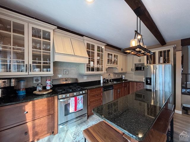 kitchen with glass insert cabinets, dark stone countertops, stainless steel appliances, premium range hood, and pendant lighting