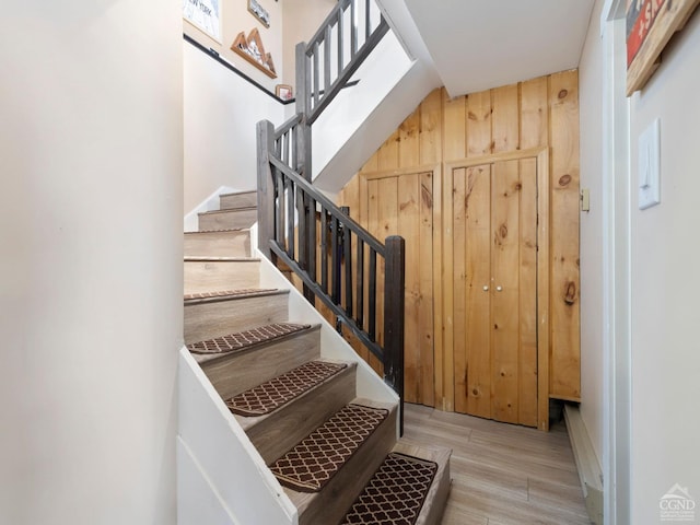 staircase featuring wood walls and wood finished floors