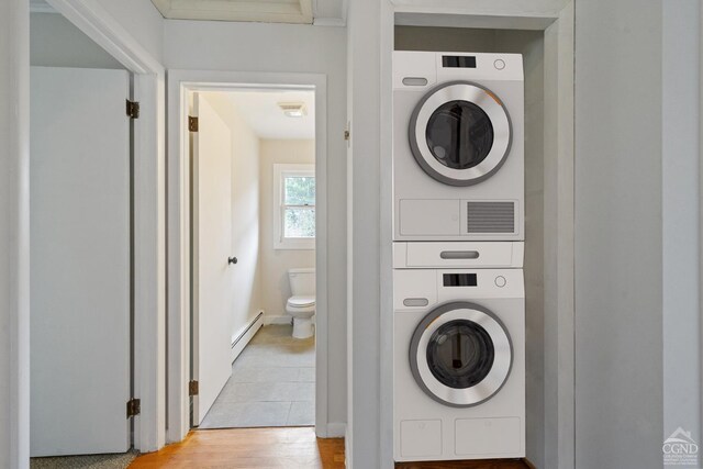 washroom featuring stacked washing maching and dryer, light hardwood / wood-style flooring, and a baseboard radiator