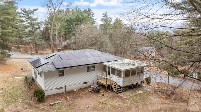 rear view of property featuring solar panels and a sunroom