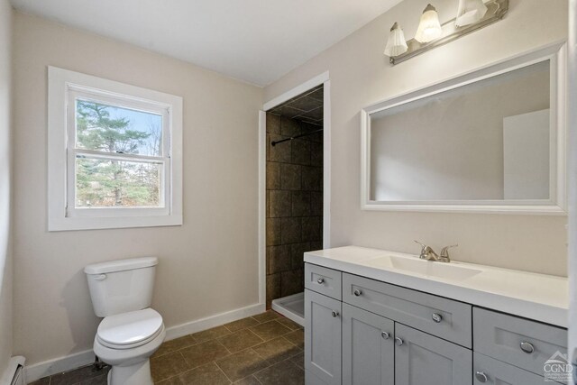 bathroom featuring tiled shower, vanity, toilet, and a baseboard heating unit